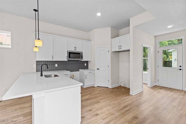 kitchen featuring sink, white cabinetry, kitchen peninsula, and decorative light fixtures