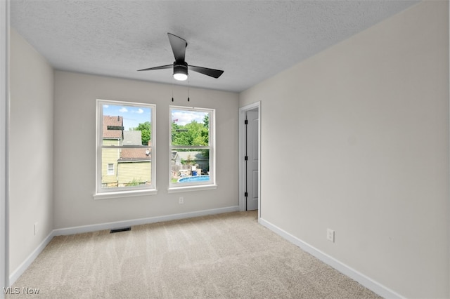 unfurnished room with a textured ceiling, light carpet, and ceiling fan