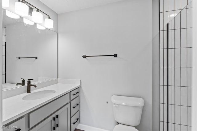 bathroom featuring vanity, toilet, and a tile shower