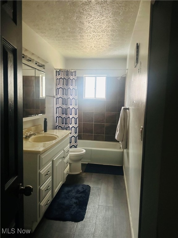 full bathroom with toilet, hardwood / wood-style floors, a textured ceiling, vanity, and shower / tub combo