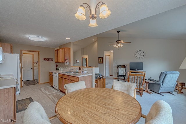 tiled dining space featuring ceiling fan with notable chandelier, a textured ceiling, sink, and vaulted ceiling