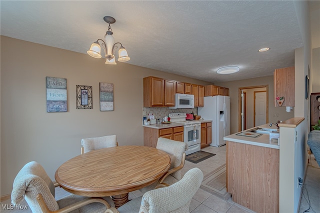 kitchen with backsplash, a notable chandelier, light tile patterned floors, hanging light fixtures, and white appliances