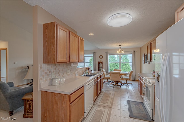 kitchen with a textured ceiling, sink, backsplash, white appliances, and decorative light fixtures