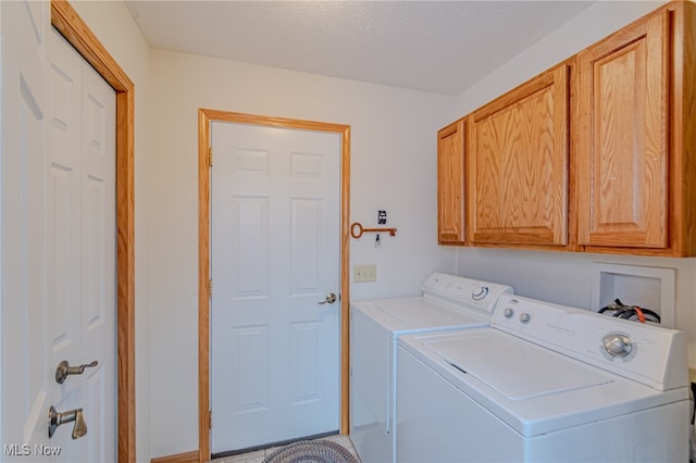 laundry area featuring cabinets, a textured ceiling, and separate washer and dryer