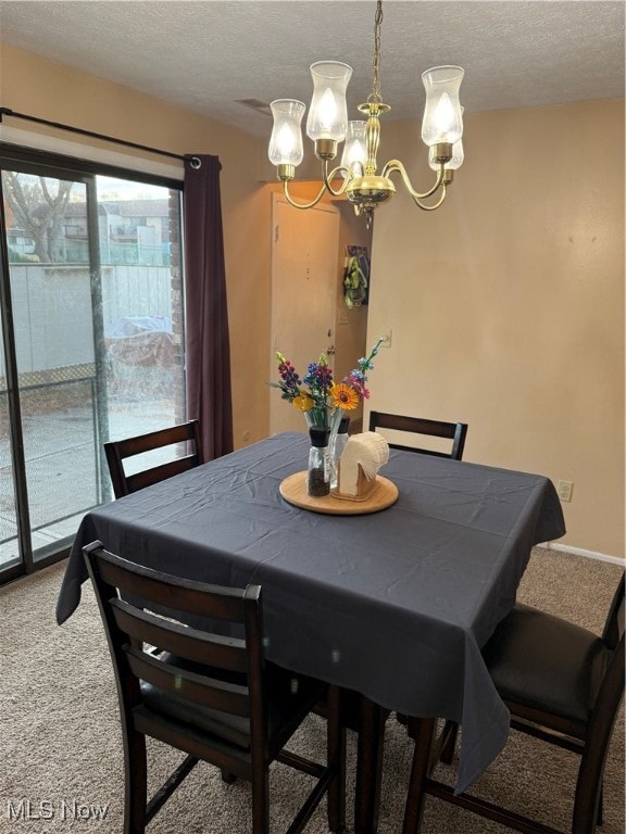 dining area featuring a textured ceiling, an inviting chandelier, and carpet floors