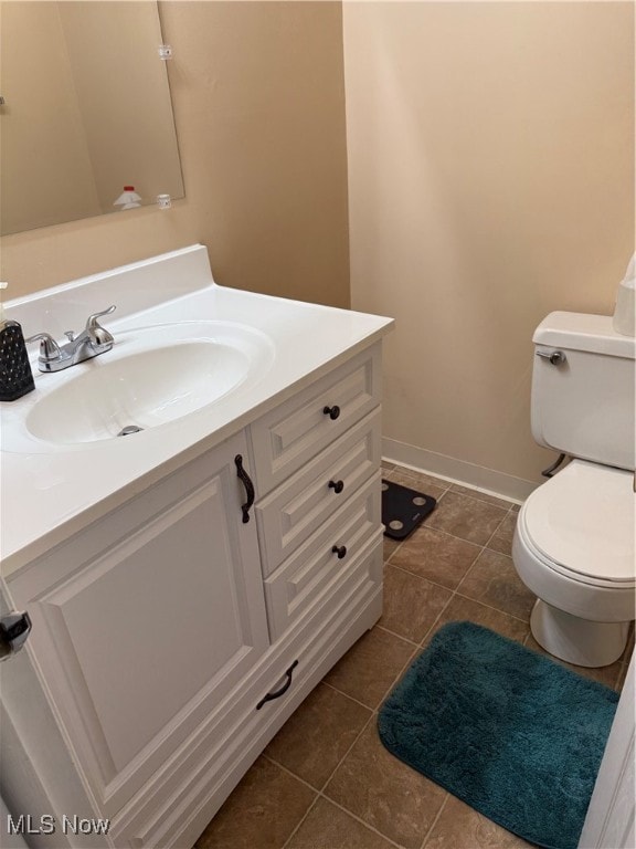 bathroom with toilet, vanity, and tile patterned floors