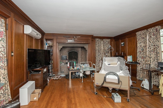 living room with crown molding, wood-type flooring, a wall mounted AC, and a brick fireplace