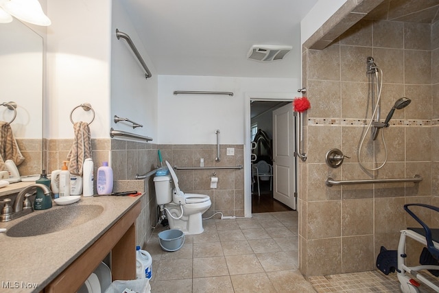 bathroom with vanity, tile patterned flooring, tiled shower, and tile walls