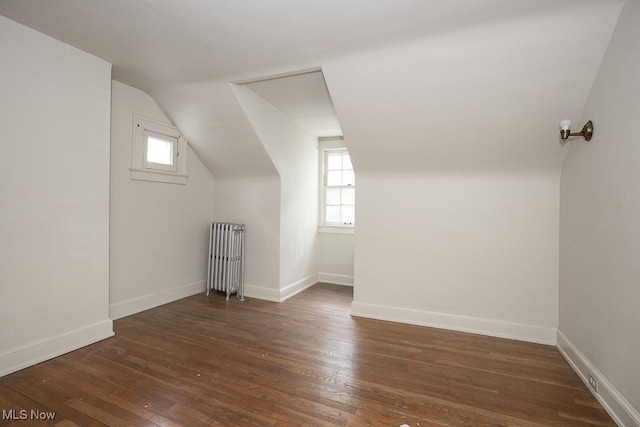 bonus room with radiator heating unit, dark wood-type flooring, and vaulted ceiling