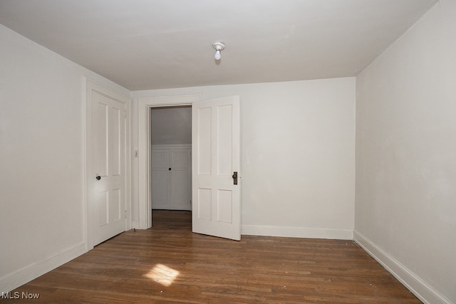 unfurnished bedroom with a closet and dark hardwood / wood-style flooring