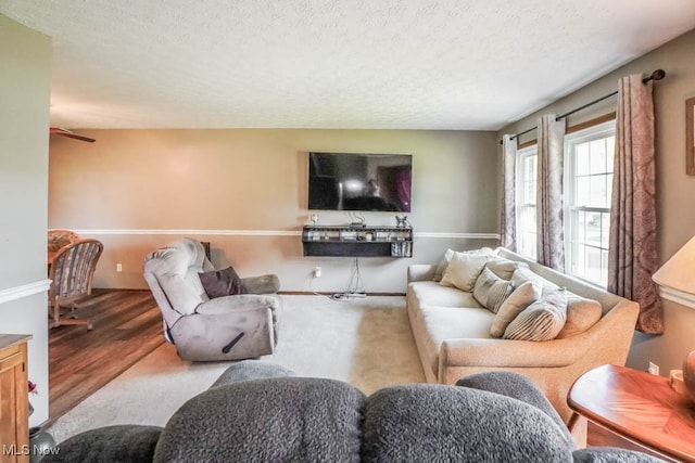 living room featuring hardwood / wood-style flooring, ceiling fan, and a textured ceiling