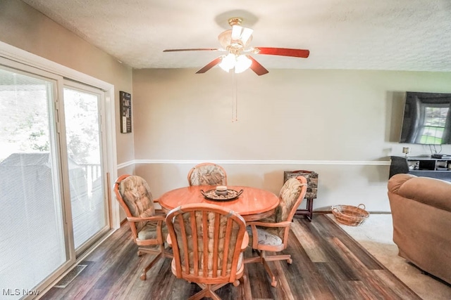 dining space with dark wood-type flooring, a textured ceiling, and ceiling fan