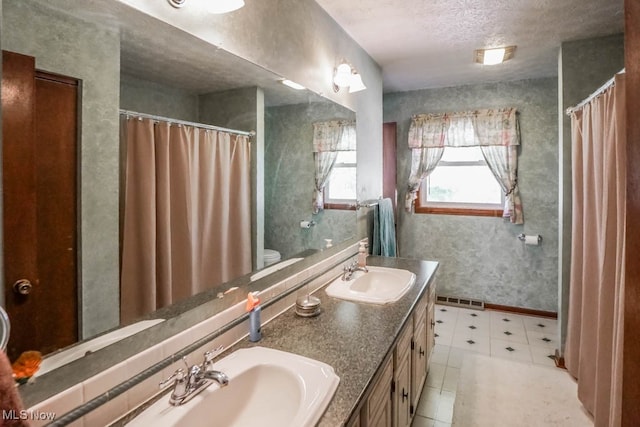 bathroom featuring tile patterned flooring, vanity, a textured ceiling, and toilet