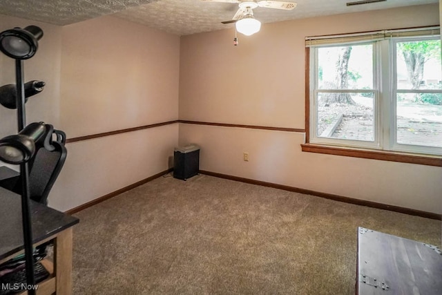 unfurnished office with carpet floors, a textured ceiling, and ceiling fan