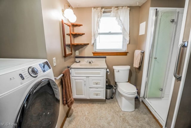 bathroom featuring toilet, vanity, a shower with door, and washer / dryer