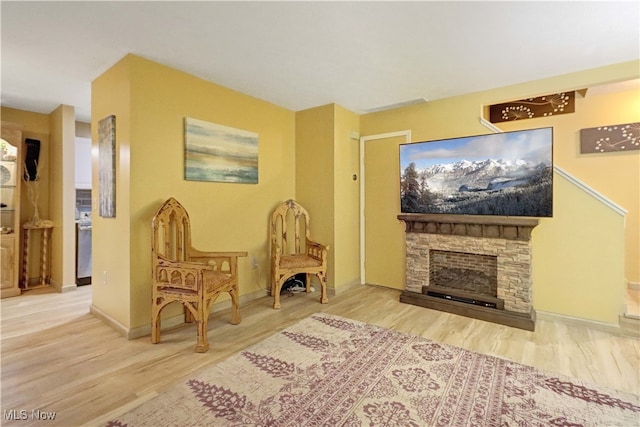 sitting room featuring a stone fireplace and hardwood / wood-style flooring