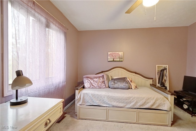 carpeted bedroom featuring multiple windows, ceiling fan, and a walk in closet