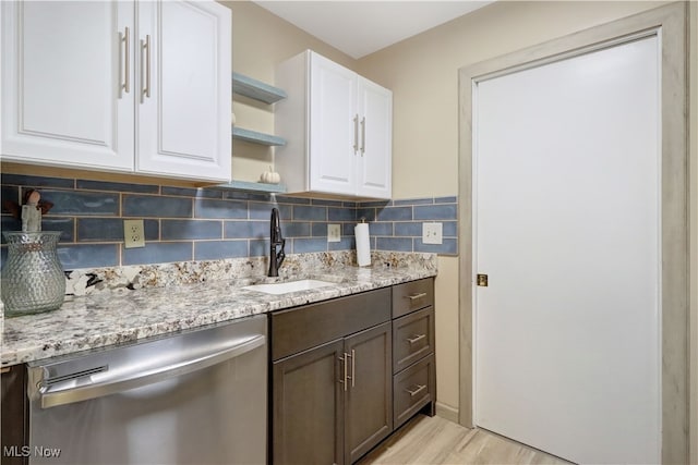 kitchen with dishwasher, sink, light stone countertops, white cabinetry, and light hardwood / wood-style flooring