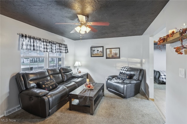 living room with ceiling fan, light colored carpet, and a textured ceiling