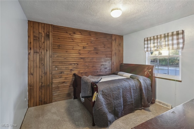 carpeted bedroom featuring wooden walls and a textured ceiling