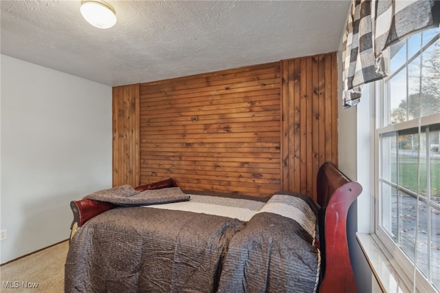 bedroom with multiple windows, wooden walls, carpet flooring, and a textured ceiling