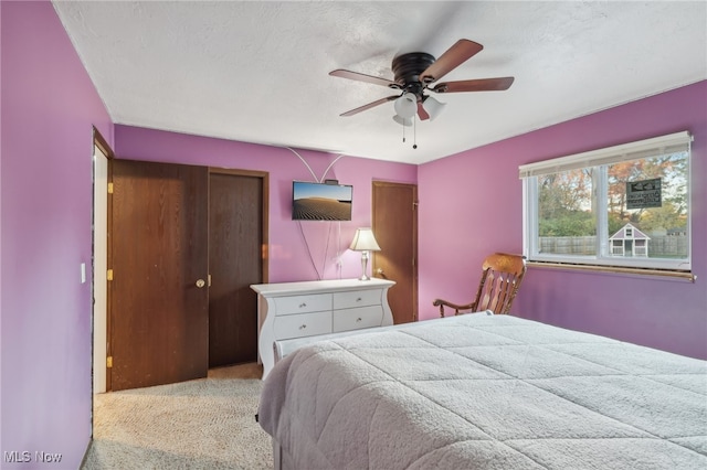 carpeted bedroom with a textured ceiling, ceiling fan, and a closet