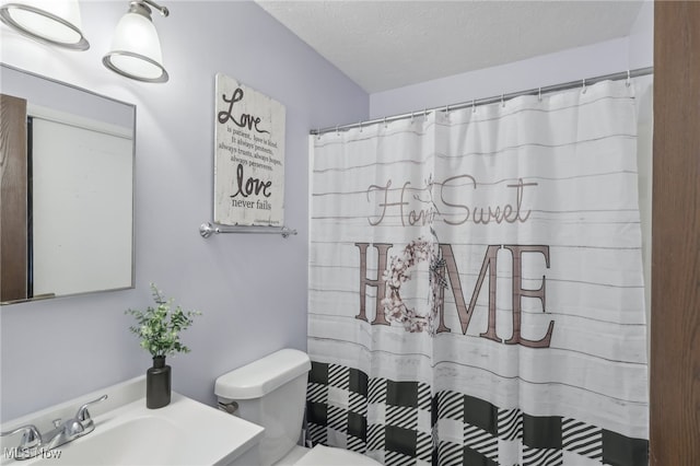 bathroom featuring toilet, sink, a shower with shower curtain, and a textured ceiling