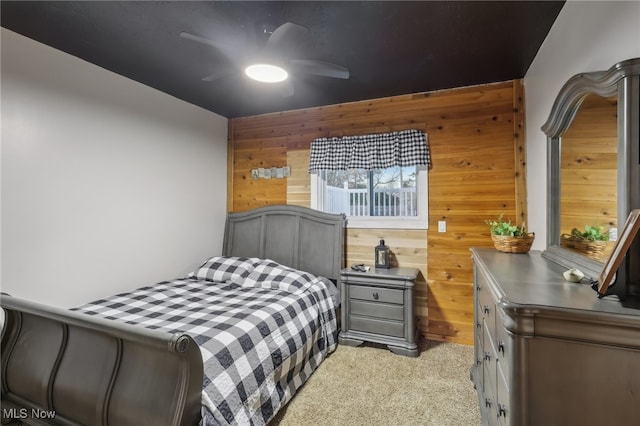 bedroom featuring wood walls, ceiling fan, and light colored carpet