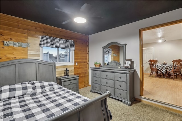 carpeted bedroom with wooden walls and ceiling fan