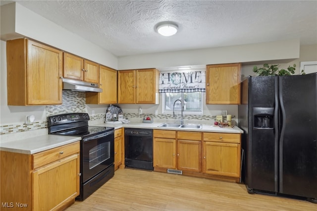 kitchen featuring black appliances, a textured ceiling, sink, backsplash, and light wood-type flooring