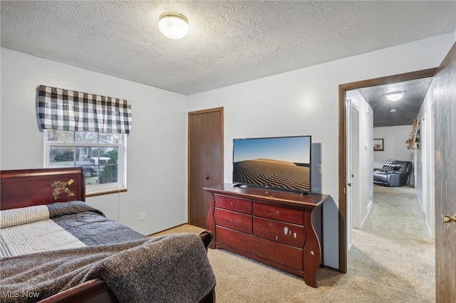 bedroom with light colored carpet and a textured ceiling