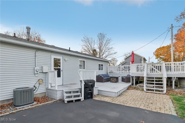 back of property featuring central AC unit, a wooden deck, and a patio area