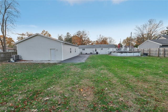 back of house with central AC, a lawn, and a covered pool