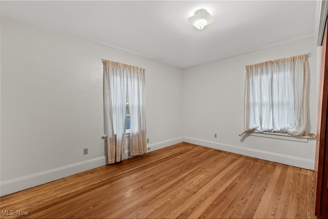 spare room featuring light wood-type flooring and a healthy amount of sunlight