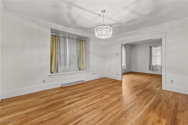 empty room featuring light wood-type flooring, a notable chandelier, and crown molding