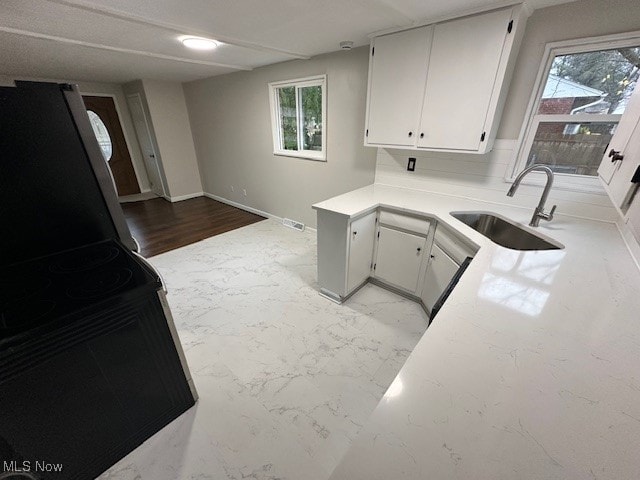 kitchen featuring white cabinets, light hardwood / wood-style flooring, sink, and stainless steel fridge