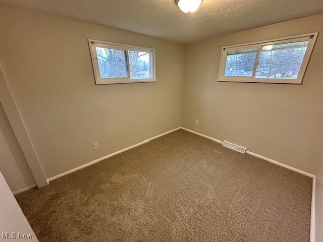 carpeted empty room featuring a textured ceiling