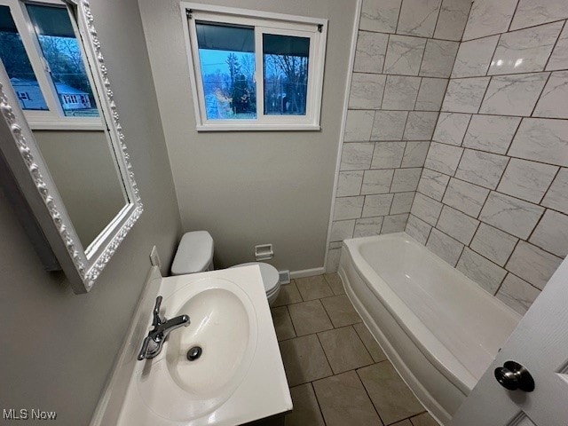 full bathroom featuring tile patterned floors, tiled shower / bath, sink, and toilet