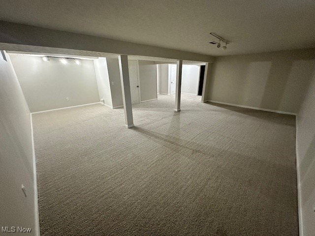 basement featuring rail lighting, a textured ceiling, and carpet