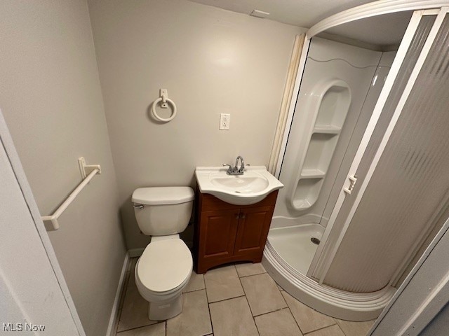 bathroom featuring walk in shower, vanity, toilet, and tile patterned flooring