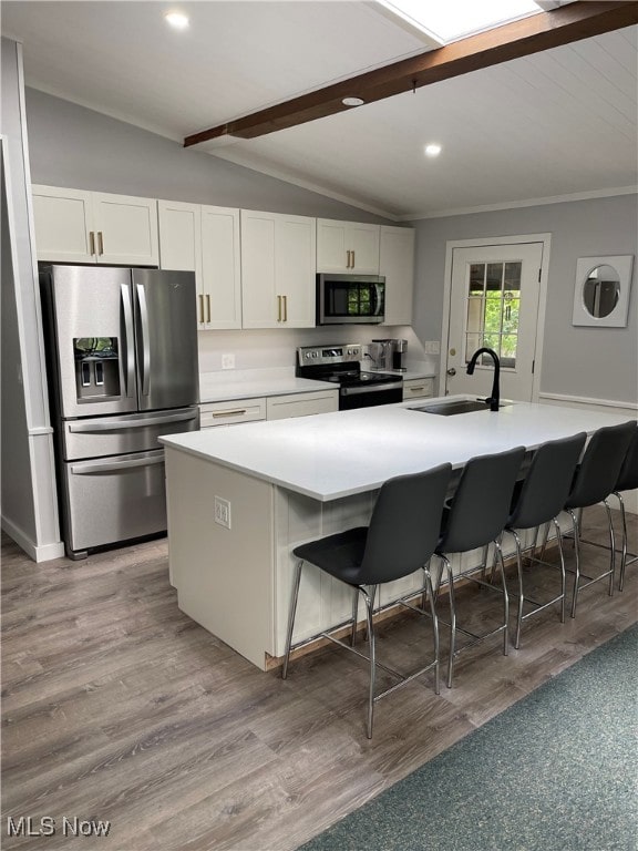 kitchen featuring stainless steel appliances, sink, white cabinetry, lofted ceiling with beams, and light wood-type flooring