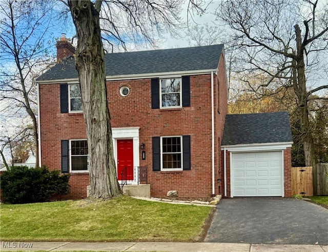 colonial house featuring a front yard and a garage