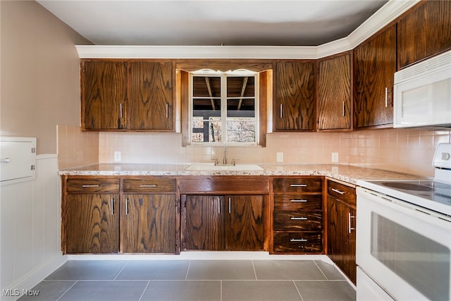 kitchen featuring sink, dark tile patterned floors, backsplash, light stone countertops, and white appliances