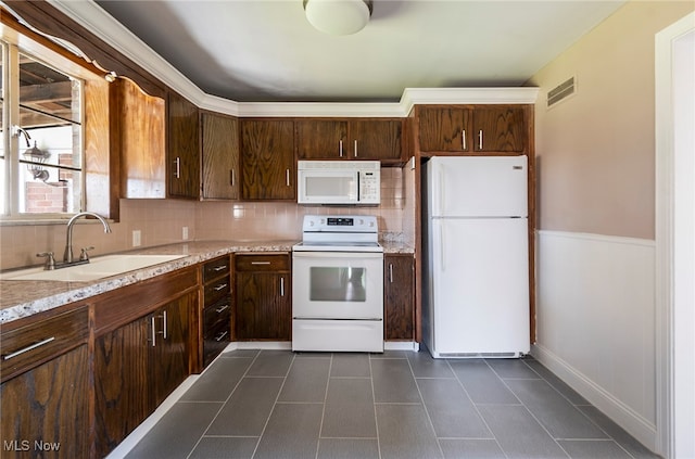 kitchen with sink, tasteful backsplash, light stone countertops, dark brown cabinets, and white appliances