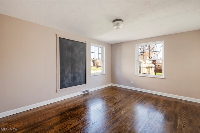 unfurnished room featuring dark hardwood / wood-style floors, a healthy amount of sunlight, and a textured ceiling