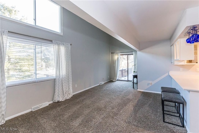 unfurnished living room with dark carpet and plenty of natural light