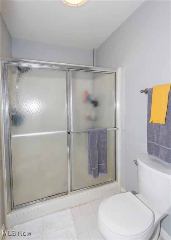 bathroom featuring toilet and a shower with shower door