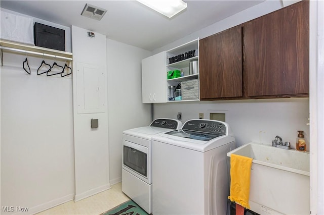 clothes washing area with washer and dryer, cabinets, and sink