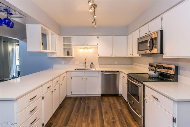 kitchen with appliances with stainless steel finishes, white cabinetry, dark hardwood / wood-style floors, and sink