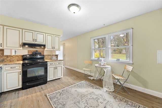 kitchen featuring light stone counters, cream cabinets, black electric range oven, and light wood-type flooring